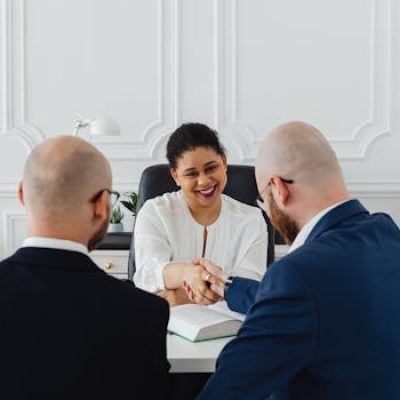 Diverse professionals in a business meeting, shaking hands across a table, indoors.